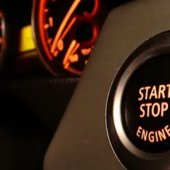 Bouton "START STOP ENGINE" illuminé, prêt à démarrer ou arrêter le moteur. Les cadrans du tableau de bord brillent en orange.