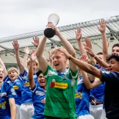 Drużyna piłkarska świętuje zwycięstwo, unosząc puchar na stadionie.