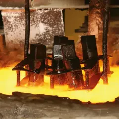 Metalowe elementy zanurzane w rozgrzanym płynie, proces hartowania. Para unosi się wokół.
