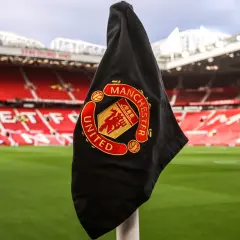 Flaga Manchester United na rogu boiska. Fani spekulują o nowych transferach, a Old Trafford czeka na wzmocnienia.