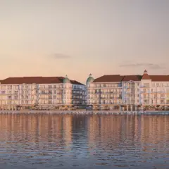 Eleganckie budynki nad wodą, z tarasami i dachami w kolorze cegły. To wizualizacja mariny royale darłowo, idealnego miejsca na wypoczynek.