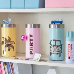 Kolorowe skarbonki DIY z motywami palmy i busa. Na półce obok stoją puszki z farbą w sprayu.