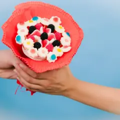 En person överlämnar en färgglad godisbukett, ett charmigt diy-projekt med blomformade geléhallon och bär.