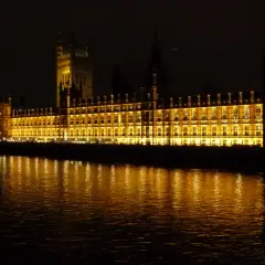 Palazzo di Westminster illuminato, un'icona di Londra by night, con riflessi dorati sull'acqua scura del Tamigi.