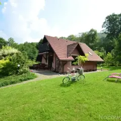 Uroczy domek z rowerem i leżakami zaprasza na noclegi w Brennej. Otoczony zielenią, idealny na wypoczynek.