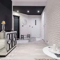 Nowoczesny przedpokój z lustrzaną komodą i ceglanymi ścianami. Inspiracje na ściany w przedpokoju.