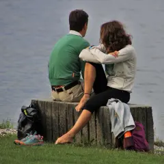 Coppia seduta sul muretto, con lo sguardo rivolto verso il lago. Un momento di quiete, forse quando l'amante si allontana, lasciando un velo di malinconia.