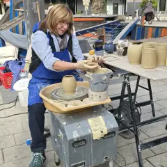 Töpferin am Werk am Hafenmarkt Heilbronn. Sie formt mit geübten Händen Ton auf ihrer Töpferscheibe.