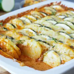 Herzhafter Zucchini Auflauf mit Kartoffeln und geschmolzenem Käse, garniert mit frischen Kräutern.