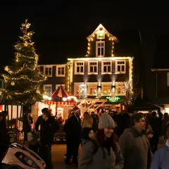 Menschen genießen den stimmungsvollen Radevormwald Weihnachtsmarkt mit beleuchtetem Baum und festlich geschmückten Häusern.