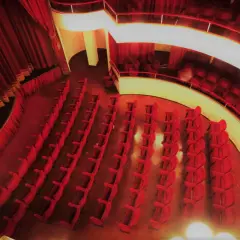 Interno del teatro cometa off, con file di poltrone rosse vuote e tende di velluto.