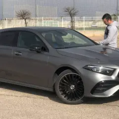 Un hombre se apoya en un elegante Mercedes Clase A gris oscuro, listo para un viaje.
