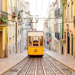 A classic yellow tram ascends a steep, cobblestone street lined with colorful buildings, a perfect scene for one day in Lisbon.