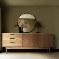 Ein Sideboard aus Holz mit Schubladen und Türen, darüber ein Spiegel und eine Lampe. So sieht ein praktisches Sideboard aus.