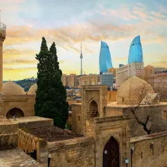 Zachód słońca nad Baku. Stare mury i minaret kontrastują z nowoczesnymi wieżowcami Flame Towers. Baku pogoda zachęca do zwiedzania.