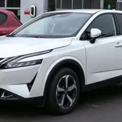 Un Nissan Qashqai blanc, parfait pour la ville, avec des jantes modernes. Ses dimensions sont idéales pour le stationnement.