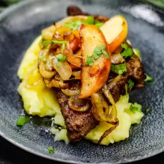 Leber Berliner Art auf Kartoffelpüree mit karamellisierten Zwiebeln und Apfelscheiben, garniert mit Petersilie.