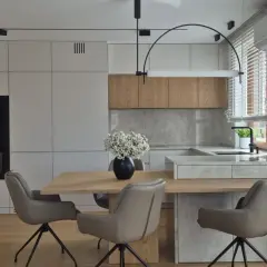 Nowoczesna kuchnia z drewnianymi frontami i kamiennym blatem. Eleganckie krzesła przy drewnianym stole. Świetne kuchnia inspiracje.