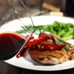 Czerwone wino w kieliszku, idealne do wieprzowiny z papryczkami chili i zieloną fasolką. Pyszny obiad czeka!
