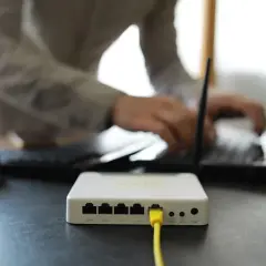 Connexion internet : faut il mettre les espaces pour la clé wifi ? Un routeur blanc est branché, une personne tape sur un ordinateur portable.