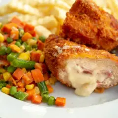 Kotlet po szwajcarsku z rozpływającym się serem, frytkami i warzywami. Pyszny obiad gotowy do spożycia.