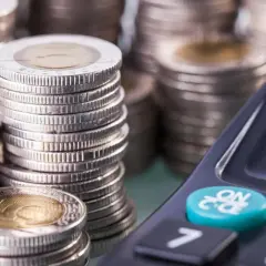 Stosy monet i kalkulator. Niewłaściwe zarządzanie finansami, np. brak spłaty zobowiązań, to czynniki, co obniża zdolność kredytową.