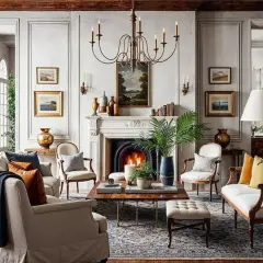 A living room with a fireplace, plush seating, and artwork evokes a sophisticated royal core aesthetic.