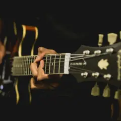 Osoba grająca na gitarze, zbliżenie na gryf i ręce.