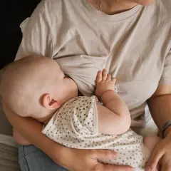 Un neonato si nutre al seno, un momento intimo che celebra il legame tra madre e figlio. Il ciclo della vita continua con l'allattamento.