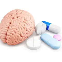Model ludzkiego mózgu obok tabletek i kapsułek, sugerujące leczenie psychotropowe.