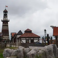 Wesołe miasteczko Hossoland kiedy otwarcie? Widok na latarnię morską, domki w stylu portowym i rzeźby.
