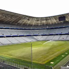 Pusta Allianz Arena, z zieloną murawą i trybunami czekającymi na kibiców.