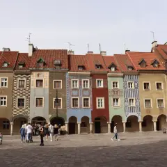 Kolorowe kamieniczki na Starym Rynku w Poznaniu, wspaniałe poznańskie atrakcje. Ludzie spacerują po brukowanym placu.