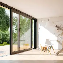 Amplias ventanas correderas modernas conectan un comedor minimalista con un jardín exuberante, mostrando diferentes tipos de ventanas modernas.