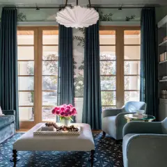 Elegant teal curtains frame French doors, showcasing a lush garden mural and reflecting current curtain trends.