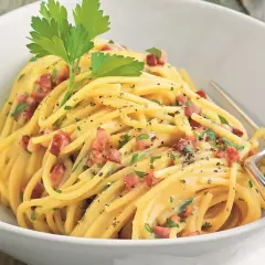 Ein Teller Spaghetti mit cremiger Sauce, Speckwürfeln und Petersilie. Ein Klassiker: Schinken Carbonara.