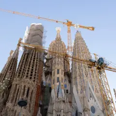 Sagrada Familia ciekawostki: wciąż w budowie, z dźwigami górującymi nad wieżami. Monumentalne dzieło Gaudiego w Barcelonie.