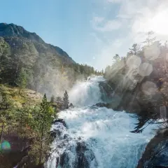 Cascada rugiente en un bosque de montaña, con rayos de sol atravesando la bruma. Un paisaje espectacular que evoca la fuerza de la naturaleza en el **pont de espagne**.