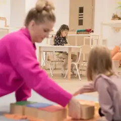 Nauczycielka pokazuje dzieciom, co to montessori, podczas zabawy klockami.