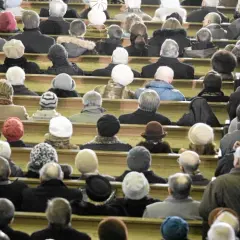 Ludzie siedzą w kościele, zastanawiając się, ile kosztują msze gregoriańskie. Wszyscy ubrani są ciepło, przygotowani na zimno.