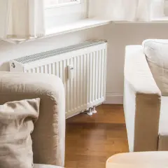 Gemütliche, helle Couch vor einer weißen Heizung, bereit für entspannte Stunden.