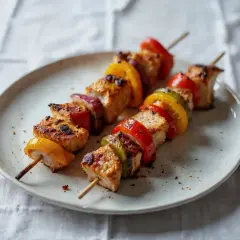 Szaszłyki z kurczaka w kolorowej marynacie z papryką i cebulą, gotowe do grillowania.