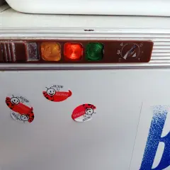 Stara lodówka Polar z kontrolkami i pokrętłem termostatu. Na drzwiach naklejki z biedronkami i napisem "Malinowy".