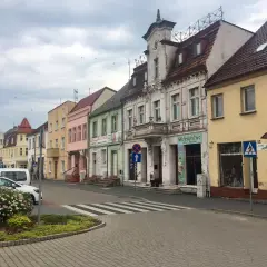 Kolorowe kamienice w **Złotnikach Kujawskich** przy ulicy, z samochodami i zielenią.