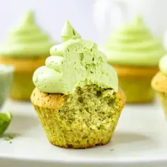 Saftige matcha cupcakes mit leuchtend grünem Topping. Ein Bissen fehlt, um die zarte Textur zu enthüllen.