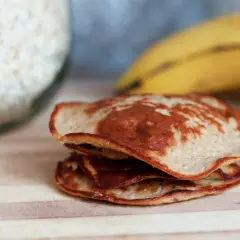 En hög med gyllenbruna bananpannkakor, redo att avnjutas. Ett enkelt bananpannkaka recept för en god frukost.