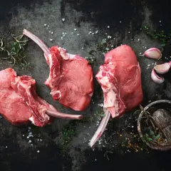 Trois belles côtes de veau crues, prêtes à être assaisonnées avec du sel, de l'ail et des herbes aromatiques.