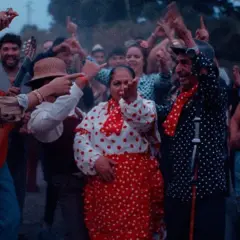 Gente bailando y cantando al son de una guitarra, como si fuera un sueño con gitanos.