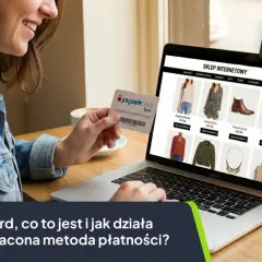 Kobieta trzyma kartę Paysafecard przed ekranem laptopa z otwartym sklepem internetowym.