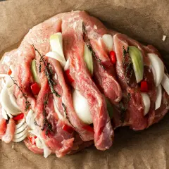 Surowa szynka wieprzowa nacięta i nadziana cebulą, papryczką chili i ziołami. Idealna do pieczenia na obiad.
